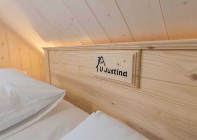 Krásná a stylová postel s logem ubytování čeká na návštěvníky v jedné z ložnic Malého apartmánu U Justina na břehu.