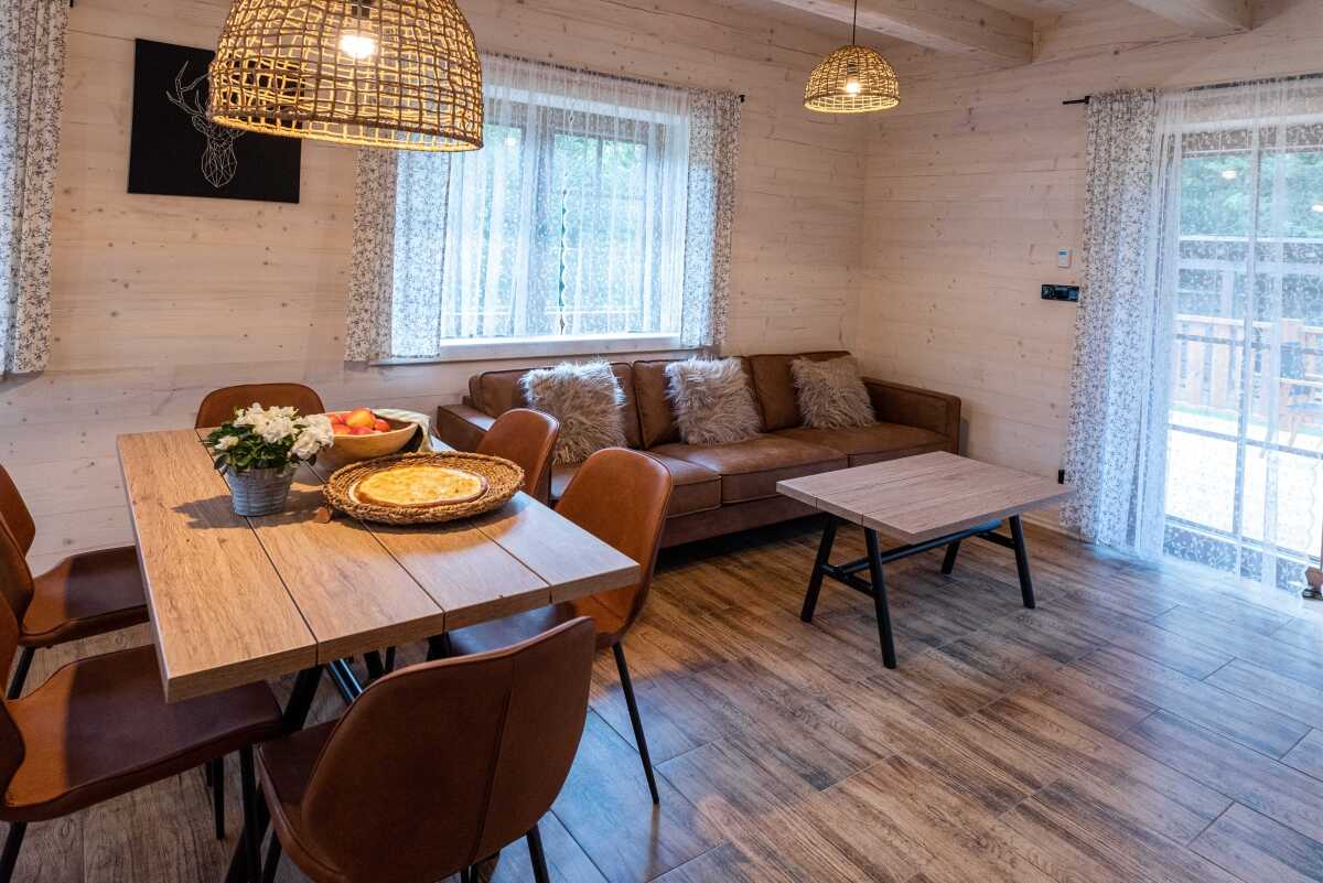 Společenská místnost s výhledem do okolí, odkud se dá vycházet na terasu Malého apartmánu doplněna o pohodlný gauč se stolkem, ručně vyrobeným jídelním stolem a židlemi.